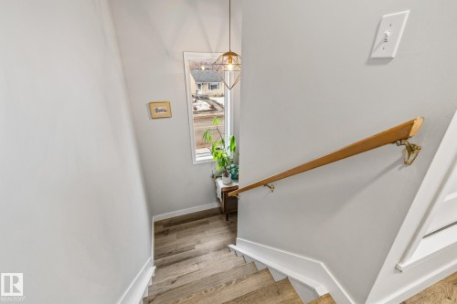 Staircase featuring light wood flooring, a wooden handrail with brass fittings, and a window providing natural light - 9321 92 Street, Edmonton, AB - Indoor Photo Showing Other Room
