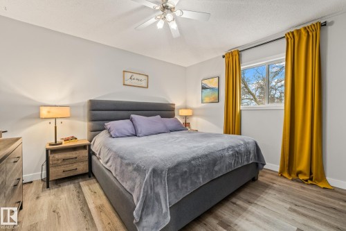 This bedroom features light-colored walls, a window with exterior views, and a ceiling fan - 9321 92 Street, Edmonton, AB - Indoor Photo Showing Bedroom