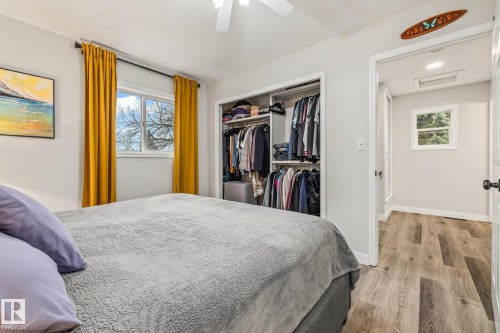 This room features a window with bright yellow curtains, a closet with built-in shelving, and light-colored flooring - 9321 92 Street, Edmonton, AB - Indoor Photo Showing Bedroom