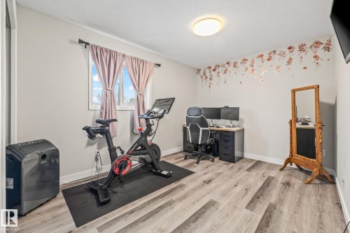 The room features light gray walls, a window with light pink curtains, and wood-style flooring - 9321 92 Street, Edmonton, AB - Indoor Photo Showing Gym Room