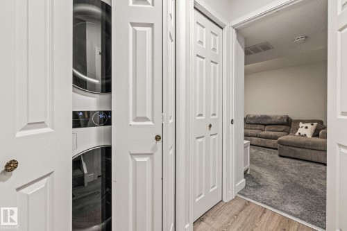 Dedicated laundry area with a stackable washer and dryer, conveniently located near a carpeted room - 9321 92 Street, Edmonton, AB - Indoor Photo Showing Other Room