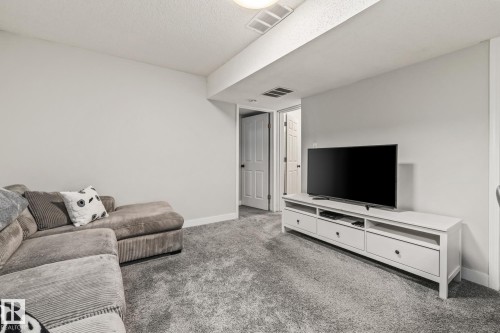Versatile room featuring light grey walls, grey carpet flooring, and a white media console - 9321 92 Street, Edmonton, AB - Indoor Photo Showing Living Room