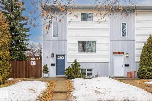 The property features a light blue and white facade with a blue entry door and a concrete walkway - 9321 92 Street, Edmonton, AB - Outdoor