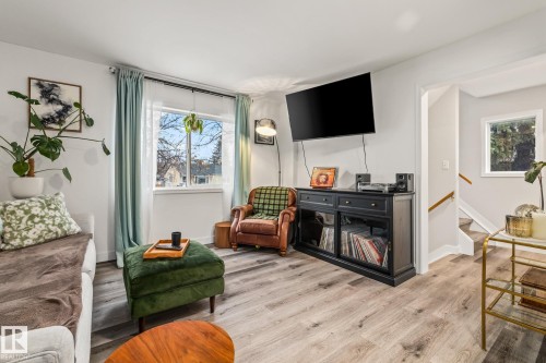 The living area features light wood-style flooring and a large window providing natural light - 9321 92 Street, Edmonton, AB - Indoor Photo Showing Living Room