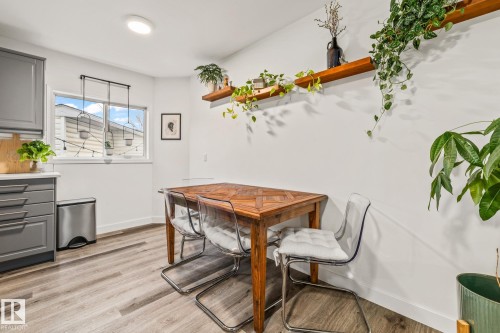 The dining area features light-colored flooring, a window providing natural light, and a wooden table - 9321 92 Street, Edmonton, AB - Indoor Photo Showing Dining Room