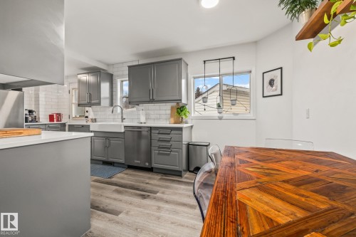 The kitchen features gray cabinetry, a white subway tile backsplash, and stainless steel appliances - 9321 92 Street, Edmonton, AB - Indoor