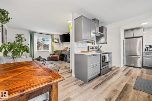 The property features an open-concept layout with light-toned flooring throughout - 9321 92 Street, Edmonton, AB - Indoor Photo Showing Kitchen With Stainless Steel Kitchen