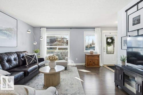 The property features hardwood floors, light-toned walls, and a white front door with a window - 16720 15 Avenue, Edmonton, AB - Indoor Photo Showing Living Room