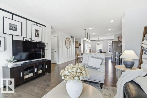 Living room featuring dark hardwood floors, recessed lighting, and a view into the kitchen with stainless steel appliances - 16720 15 Avenue, Edmonton, AB - Indoor Photo Showing Living Room