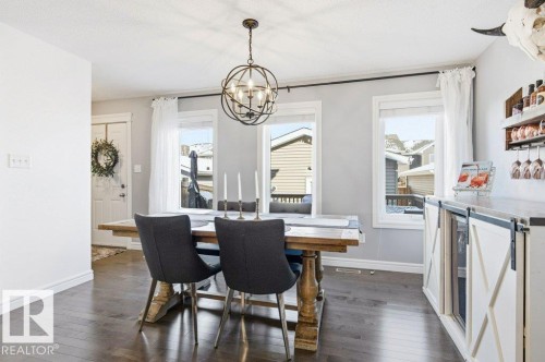 This inviting dining area features dark hardwood flooring and light-colored walls, creating a bright and open atmosphere - 16720 15 Avenue, Edmonton, AB - Indoor Photo Showing Dining Room