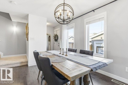 The property features hardwood flooring, a dining area with a modern chandelier, and windows providing natural light - 16720 15 Avenue, Edmonton, AB - Indoor Photo Showing Dining Room