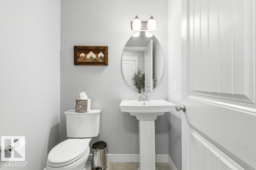 Bathroom featuring a pedestal sink with a mirror, a toilet, and light-colored walls - 16720 15 Avenue, Edmonton, AB - Indoor Photo Showing Bathroom