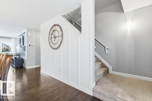 The property features hardwood flooring in the main living space and a carpeted staircase with a white handrail - 16720 15 Avenue, Edmonton, AB - Indoor Photo Showing Other Room