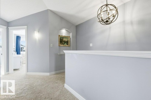 The property features soft grey walls, light-colored carpet, and a decorative orb chandelier - 16720 15 Avenue, Edmonton, AB - Indoor Photo Showing Other Room