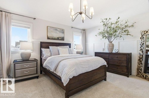 The bedroom features a light-colored carpet, white walls with wainscoting, and large windows with white trim - 16720 15 Avenue, Edmonton, AB - Indoor Photo Showing Bedroom