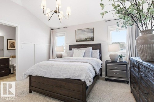 Bedroom with light-colored carpeting, white walls with wainscoting, and a dark wood bed frame - 16720 15 Avenue, Edmonton, AB - Indoor Photo Showing Bedroom