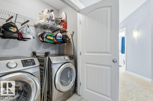 The laundry area features front-loading washing machines and overhead wire shelving - 16720 15 Avenue, Edmonton, AB - Indoor Photo Showing Laundry Room