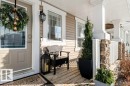 The property features a welcoming porch with a wood deck, stone-accented pillars, and a decorative outdoor lantern - 16720 15 Avenue, Edmonton, AB  - Outdoor With Deck Patio Veranda With Exterior 