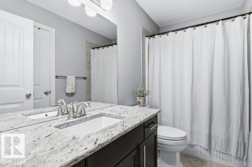 The bathroom features a vanity with a white granite countertop and an integrated rectangular sink - 16720 15 Avenue, Edmonton, AB - Indoor Photo Showing Bathroom