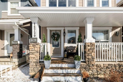 The property features a welcoming front porch with stone-clad columns, white railings, and a staircase leading to the entrance - 16720 15 Avenue, Edmonton, AB - Outdoor With Deck Patio Veranda With Facade