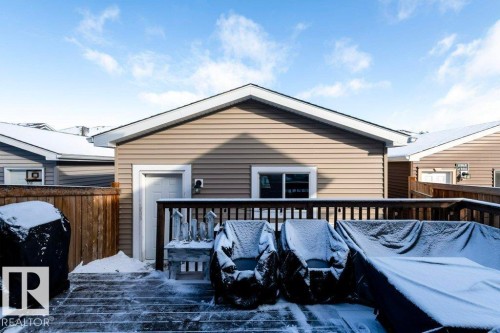 The property includes a wooden deck, a wooden fence, and a beige vinyl-sided exterior with white trim - 16720 15 Avenue, Edmonton, AB - Outdoor With Deck Patio Veranda With Exterior