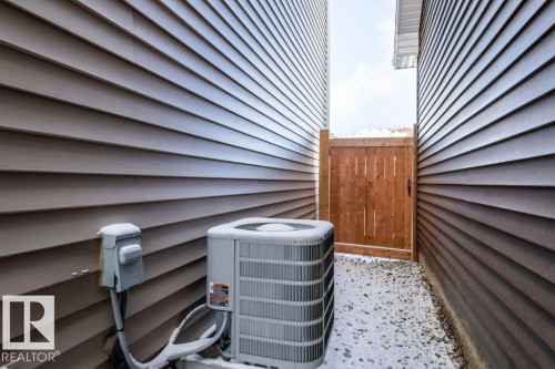 The property features exterior siding, a wooden fence, and a gravel path - 16720 15 Avenue, Edmonton, AB - Outdoor With Exterior
