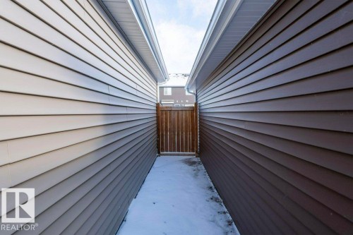 The property features siding in two distinct colors and a wooden gate - 16720 15 Avenue, Edmonton, AB - Outdoor With Exterior