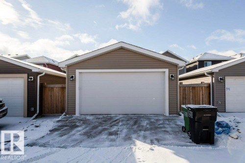The property includes a detached garage with a white garage door, beige siding, and two exterior lights - 16720 15 Avenue, Edmonton, AB - Outdoor With Exterior