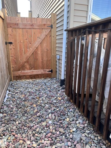 The property includes a wooden privacy fence with a gate, a gravel pathway, and a wooden deck with railing - 16720 15 Avenue, Edmonton, AB - Indoor