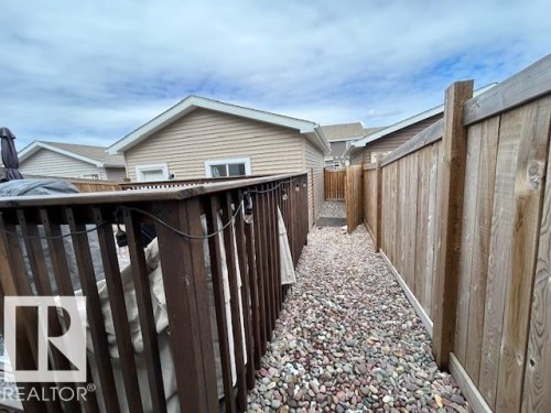 The property includes a fenced outdoor area with a gravel path, providing privacy and outdoor space - 16720 15 Avenue, Edmonton, AB - Outdoor