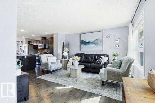 The property features an open concept living area with hardwood floors and light gray walls - 16720 15 Avenue, Edmonton, AB - Indoor Photo Showing Living Room
