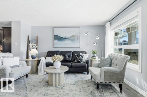 Living area featuring a large window, dark wood floors, and a light-colored area rug - 16720 15 Avenue, Edmonton, AB - Indoor Photo Showing Living Room