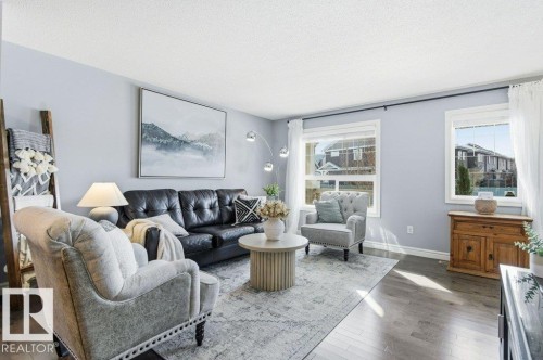 The living space features light gray walls, hardwood flooring, and two windows providing natural light - 16720 15 Avenue, Edmonton, AB - Indoor Photo Showing Living Room
