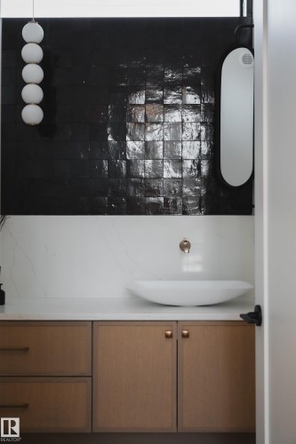 Modern bathroom vanity featuring a white vessel sink, a wall-mounted faucet, and light wood cabinetry with drawers and cupboards - 13804 85 Avenue, Edmonton, AB - Indoor