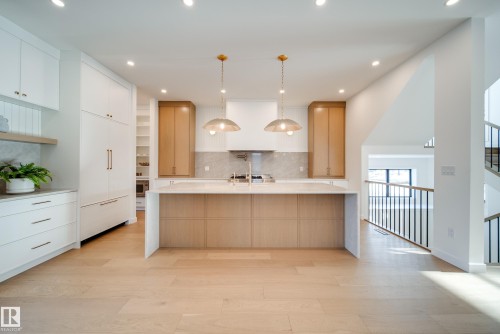 The kitchen features a large island with a light-colored countertop, recessed lighting, and two pendant lights - 13804 85 Avenue, Edmonton, AB - Indoor Photo Showing Kitchen