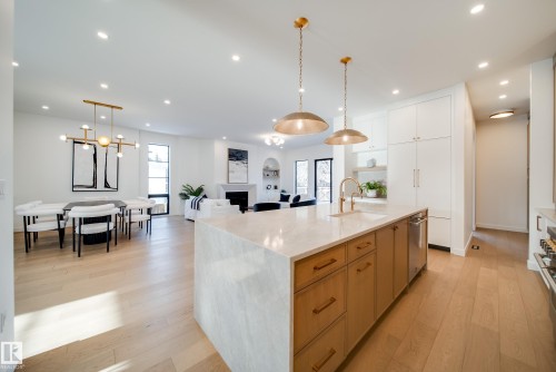 The kitchen features an expansive island with a light-colored countertop and wooden cabinetry, accompanied by pendant lighting fixtures - 13804 85 Avenue, Edmonton, AB - Indoor Photo Showing Kitchen With Upgraded Kitchen