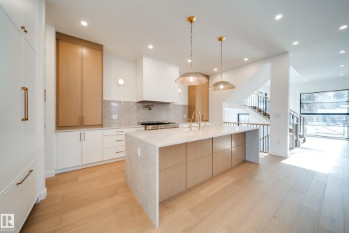 Gourmet kitchen featuring a large central island with a waterfall edge countertop, light wood cabinetry, and recessed lighting - 13804 85 Avenue, Edmonton, AB - Indoor Photo Showing Kitchen With Upgraded Kitchen
