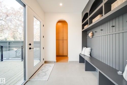 Entryway featuring a built-in bench with storage, floor-to-ceiling glass doors, and a decorative arched hallway - 13804 85 Avenue, Edmonton, AB - Indoor Photo Showing Other Room