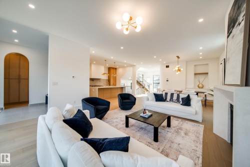 This open-concept living area features light-colored flooring, recessed lighting, and a modern chandelier - 13804 85 Avenue, Edmonton, AB - Indoor Photo Showing Living Room