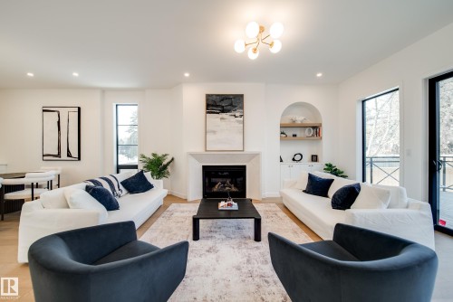 The property features an inviting living space with light wood flooring, a fireplace, and an arched built-in shelving unit - 13804 85 Avenue, Edmonton, AB - Indoor Photo Showing Living Room With Fireplace