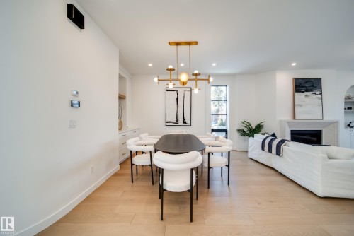 This open-concept living area features light-toned hardwood flooring, recessed lighting, and a modern chandelier - 13804 85 Avenue, Edmonton, AB - Indoor With Fireplace