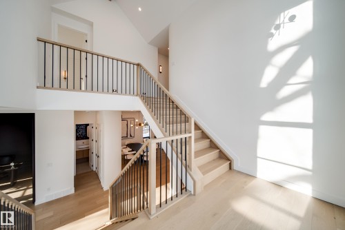 Expansive entryway featuring light wood flooring, a multi-level staircase with modern black metal balusters and light wood handrails, and high ceilings - 13804 85 Avenue, Edmonton, AB - Indoor Photo Showing Other Room