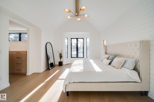 This property features a room with a vaulted ceiling, light hardwood flooring, and a bay window with dark frames - 13804 85 Avenue, Edmonton, AB - Indoor Photo Showing Bedroom