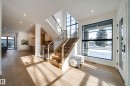 Entryway featuring light hardwood floors, a prominent staircase with dark metal railings and wooden banisters, and a large window providing ample natural light - 13804 85 Avenue, Edmonton, AB  - Indoor Photo Showing Other Room 