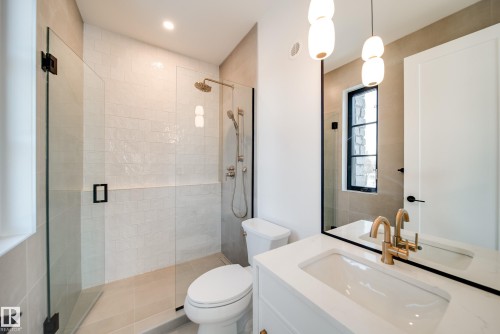Bathroom featuring a glass-enclosed shower, a vanity with a white countertop and sink, and a large mirror with a black frame - 13804 85 Avenue, Edmonton, AB - Indoor Photo Showing Bathroom