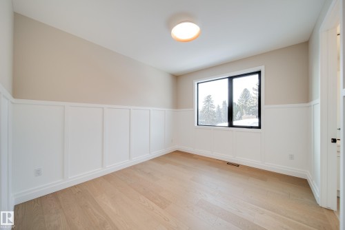 This room features light hardwood flooring, wainscoting, and a window with a dark frame - 13804 85 Avenue, Edmonton, AB - Indoor Photo Showing Other Room