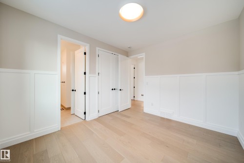 This room features light-colored hardwood flooring, white wainscoting, and white doors with black hardware - 13804 85 Avenue, Edmonton, AB - Indoor Photo Showing Other Room