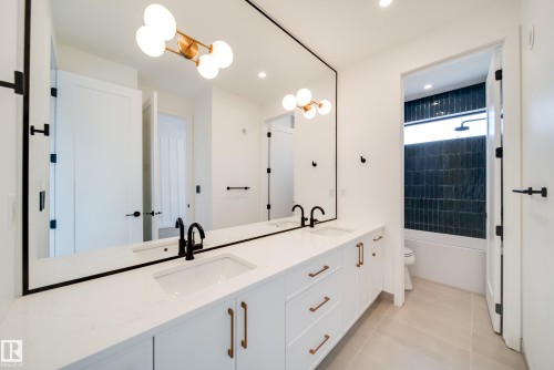 Bathroom featuring a dual vanity with white cabinetry, light-colored countertops, and black faucets - 13804 85 Avenue, Edmonton, AB - Indoor
