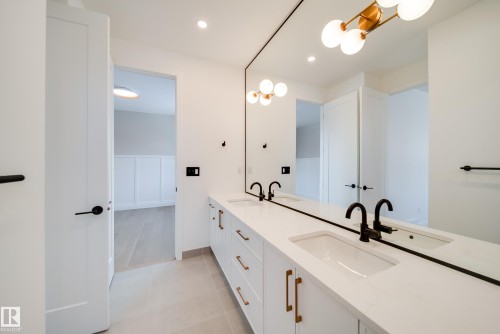 The bathroom features a double vanity with white countertops, integrated sinks, and black fixtures - 13804 85 Avenue, Edmonton, AB - Indoor