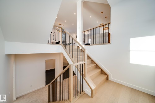 The property features light wood flooring and a staircase with light wood banisters and black metal spindles - 13804 85 Avenue, Edmonton, AB - Indoor Photo Showing Other Room